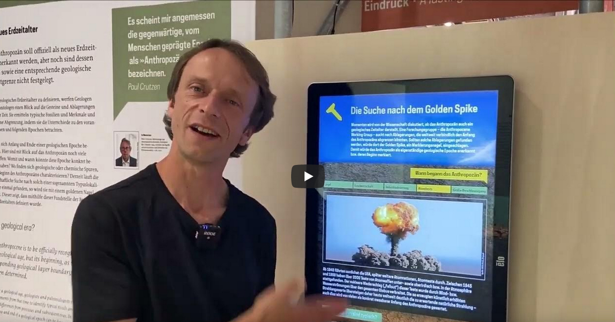 Guide zeigt auf Bildschirm in der Sonderausstellung Anthropozän