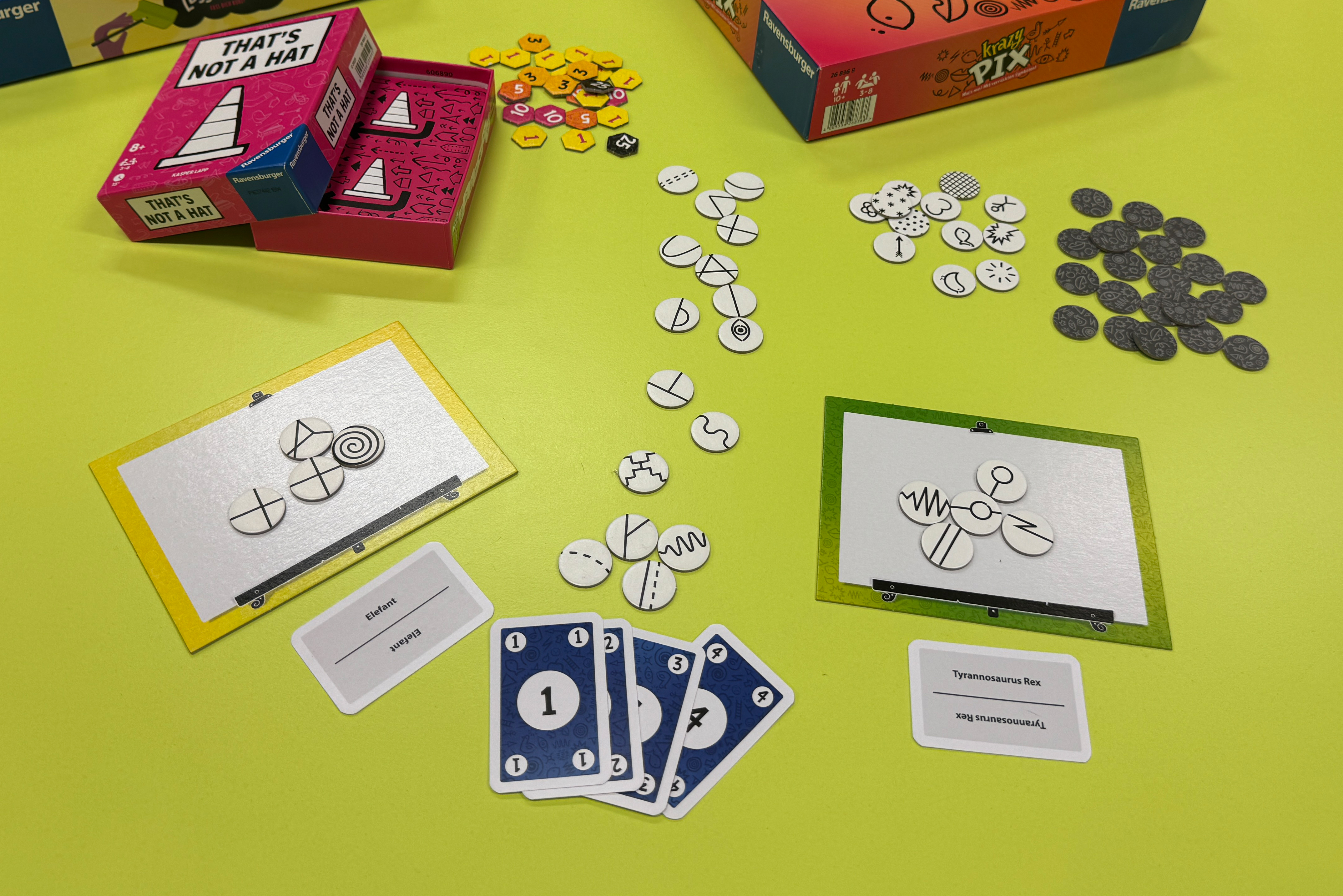 Ein auf einem Tisch ausgebreitetes Spiel mit Karten und verschiedenen Symbolplättchen